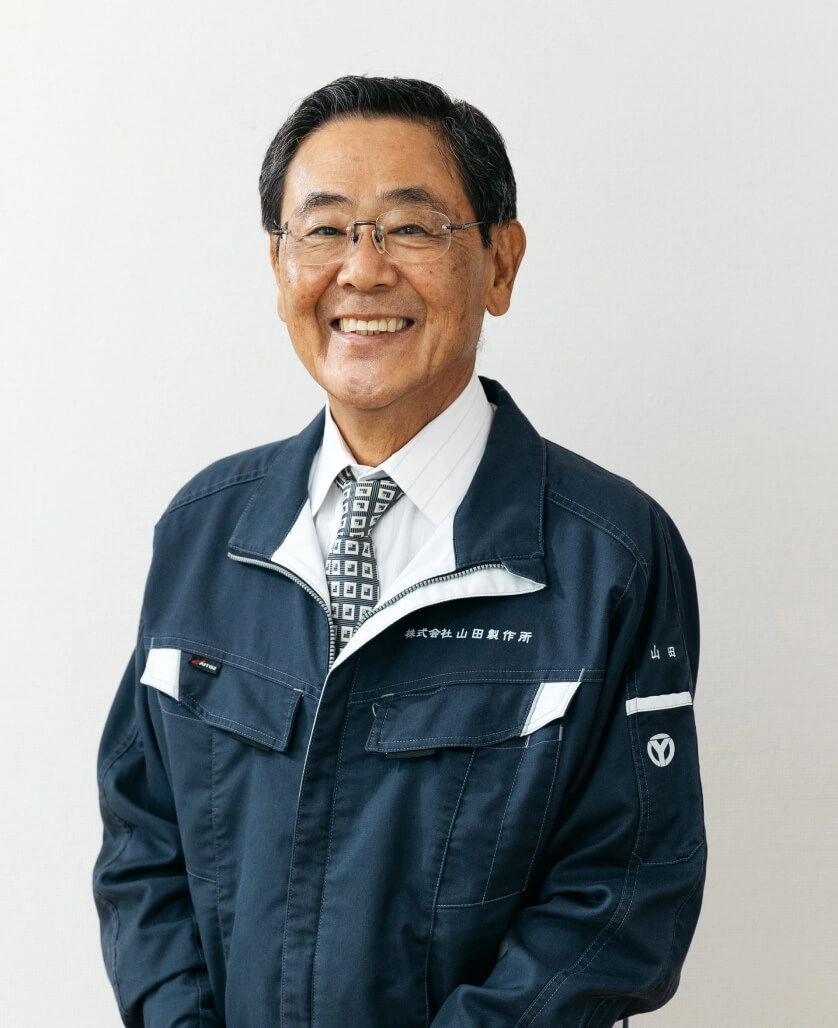 株式会社山田製作所の代表取締役社長が作業着姿で写っているポートレート写真