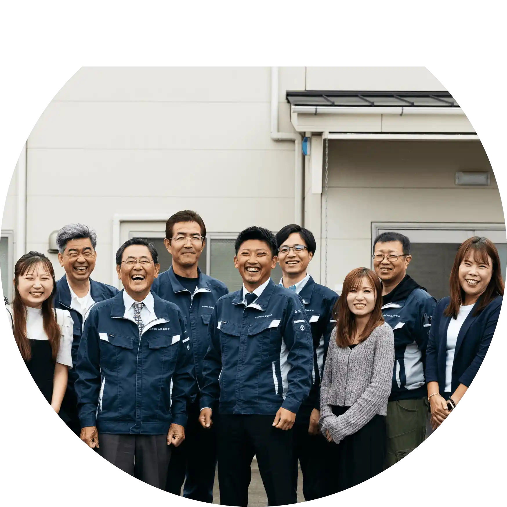 株式会社山田製作所の社員が工場前で笑顔で並んで写っている集合写真