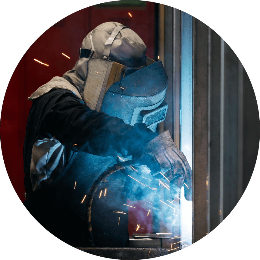 工場内で防護具を着用し溶接作業をしている人物の写真