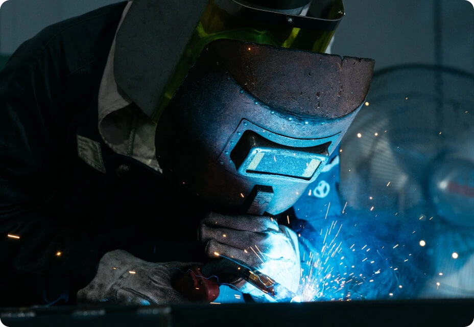 防護マスクを着用した作業員が金属の溶接作業をしている様子