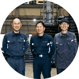 工場内で作業着を着た複数人の笑顔の男性