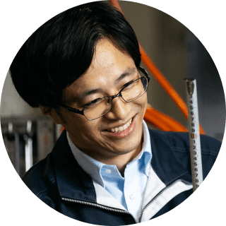 工場内で機械を操作している笑顔の男性